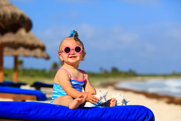 Schattig klein babymeisje met schelpen op tropisch strand — Stockfoto