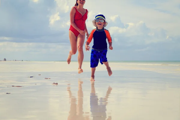 Madre e hijo corriendo en el agua en la playa — Foto de Stock