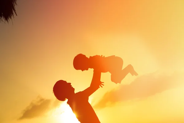 Padre e piccolo figlio silhouette giocare al tramonto — Foto Stock