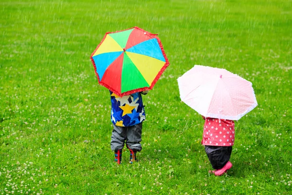 Niños con sombrillas de colores en el día lluvioso — Foto de Stock