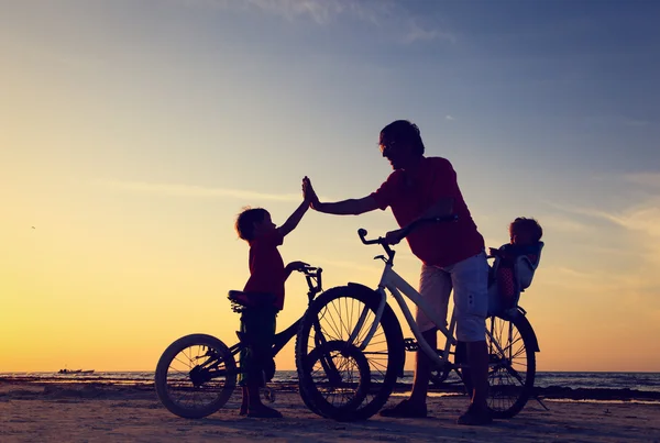 Padre con dos hijos en bicicleta al atardecer —  Fotos de Stock