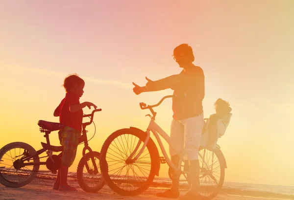 Pai com dois filhos de bicicleta ao pôr-do-sol — Fotografia de Stock