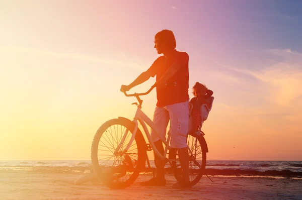 Silhueta de pai e bebê de bicicleta ao pôr do sol — Fotografia de Stock