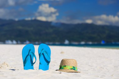 Hasır şapka ve bir kum plajı üzerinde flip flop