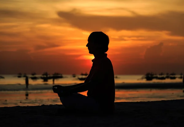 Jeune homme faisant du yoga sur la plage du coucher du soleil — Photo