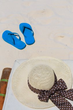 Hasır şapka ve bir kum plajı üzerinde flip flop