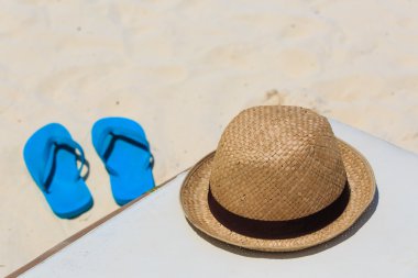 Hasır şapka ve bir kum plajı üzerinde flip flop