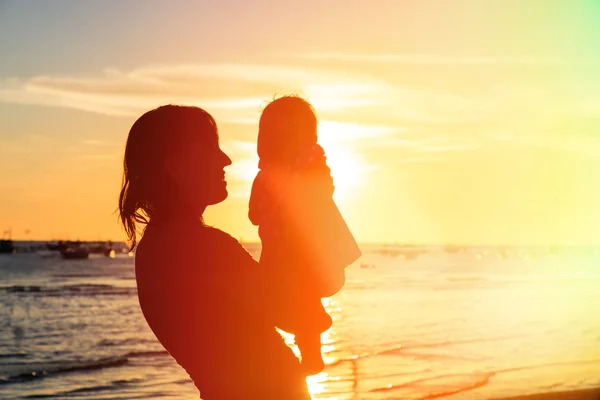 Mère heureuse et bébé s'amuser à la plage du coucher du soleil — Photo