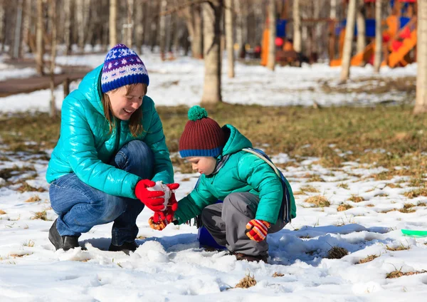 Мать и сын строят снеговика зимой — стоковое фото