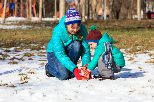 Mother and son building snowman in winter — Stock Photo, Image