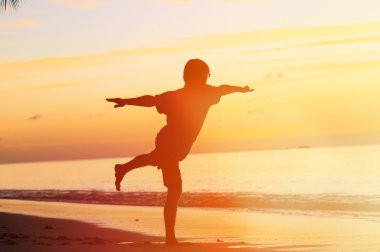 Gün batımında yoga yaparken genç adam silüeti