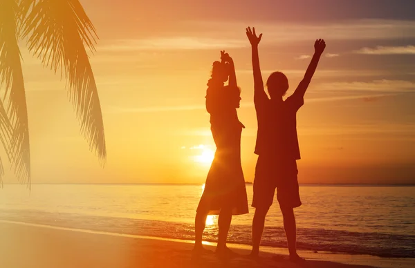 Casal feliz com criança pequena na praia do pôr do sol — Fotografia de Stock