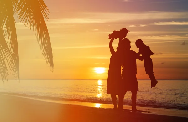 Šťastná rodina s dvěma dětmi bavíte na pláži při západu slunce — Stock fotografie