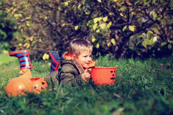 Liten pojke leker med pumpa och halloween leksaker — Stockfoto