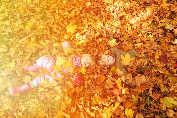 Діти розважаються восени осіннім листям — стокове фото