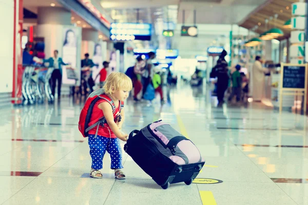 Liten flicka med resväska resor på flygplatsen — Stockfoto