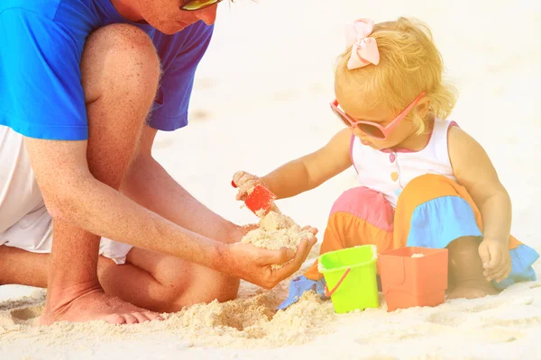 Père et petite fille jouant avec le sable sur la plage — Photo