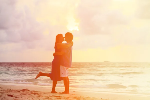 Joven pareja romántica en la playa al atardecer — Foto de Stock