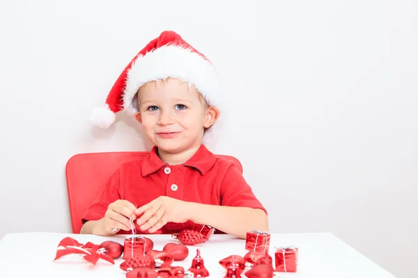 Μικρό αγόρι στο καπέλο Santa διαλογής χριστουγεννιάτικα δώρα — Φωτογραφία Αρχείου