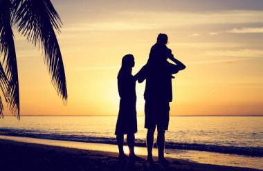 günbatımı tropikal plaj, küçük çocuk ile genç Çift