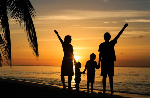 Gelukkig gezin met twee kinderen op zonsondergang tropisch strand — Stockfoto