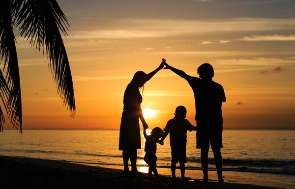 Gelukkig jonge ouders maken huis voor kinderen bij zonsondergang — Stockfoto