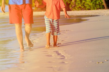 Baba ve oğul kuma ayak izi bırakarak Sahilde yürüyüş