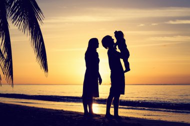 günbatımı tropikal plaj, küçük çocuk ile genç Çift