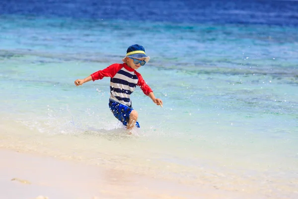 Piccolo ragazzo spruzzi d'acqua sulla spiaggia tropicale — Foto Stock