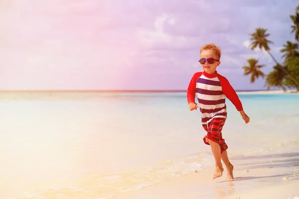 Piccolo ragazzo spruzzi d'acqua sulla spiaggia tropicale — Foto Stock