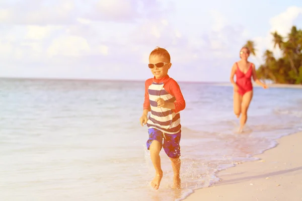 Madre e figlio che corrono in acqua sulla spiaggia — Foto Stock