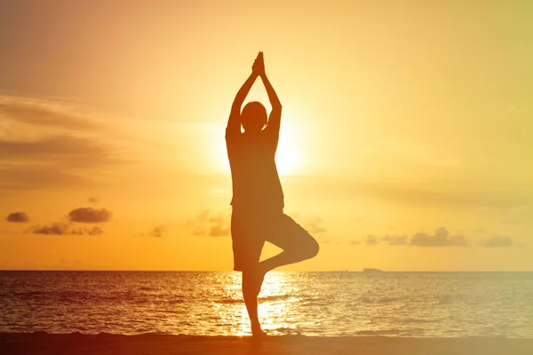 Silhouette of young man doing yoga at sunset — Stock Photo, Image