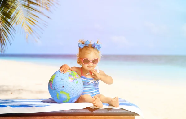 Маленькая девочка с глобусом и игрушечным самолетом на пляже — стоковое фото