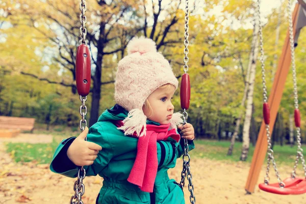 Bonito menina se divertindo no balanço no outono — Fotografia de Stock