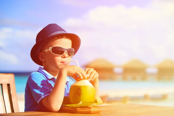 Malý chlapec pití kokosový koktejl na tropické pláži — Stock fotografie