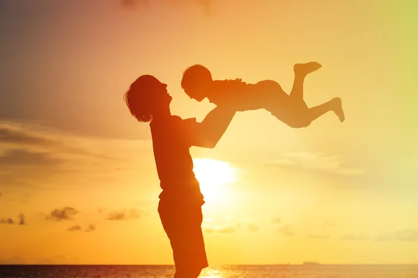 Father and little son silhouettes play at sunset — Stock Photo, Image