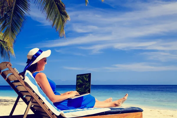 Νεαρή γυναίκα με φορητό υπολογιστή σε τροπική παραλία — Φωτογραφία Αρχείου