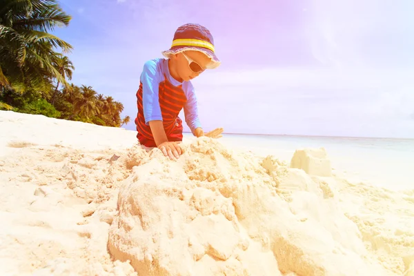 Piccolo ragazzo costruzione castello di sabbia sulla spiaggia tropicale — Foto Stock