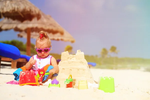 Mignon petite fille bâtiment Sandcastle sur la plage — Photo