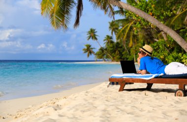 tropik sahil üstünde laptop ile genç adam