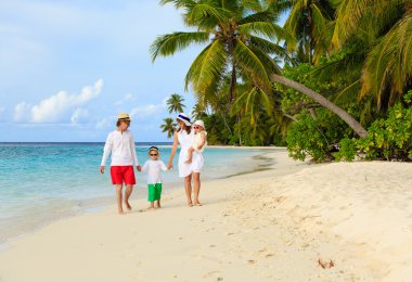 tropikal kumsalda yürüyen iki çocuklu aile