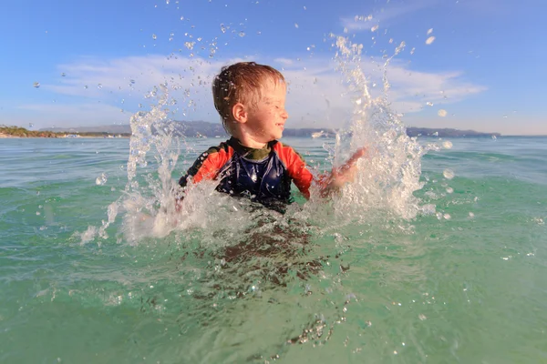Menino brincando com a água na praia — Fotografia de Stock