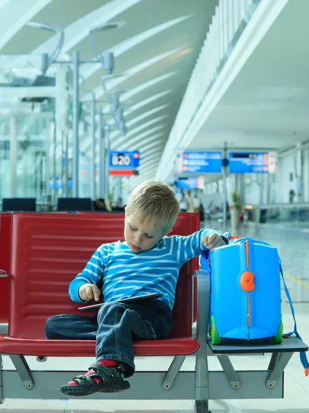 Niño pequeño con almohadilla táctil esperando en el aeropuerto — Foto de Stock