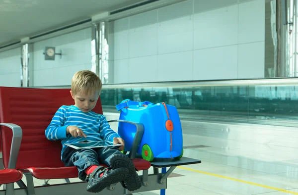 Niño pequeño con almohadilla táctil esperando en el aeropuerto —  Fotos de Stock