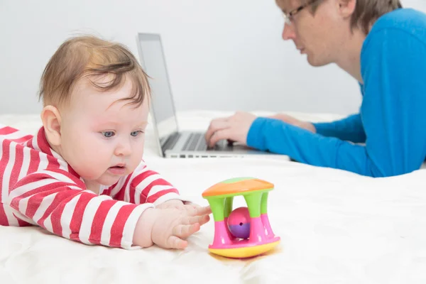 Barn leker medan far arbetar på laptop — Stockfoto