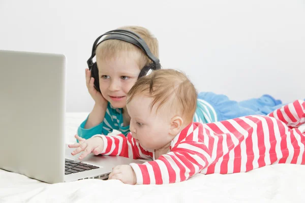 Kleines Mädchen mit Bruder schaut auf Laptop — Stockfoto