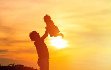 Baba ve küçük kızı siluetleri gün batımında