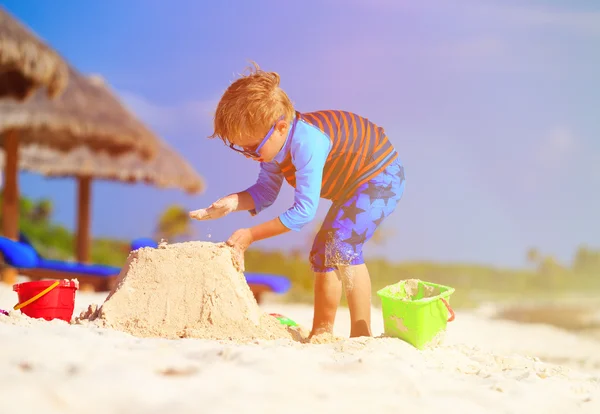 Piccolo ragazzo costruzione castello di sabbia sulla spiaggia — Foto Stock