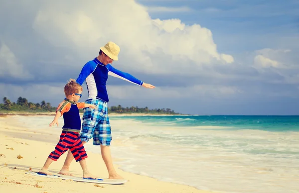 Отец и маленький сын практикуют серфинг Positin на пляже — стоковое фото