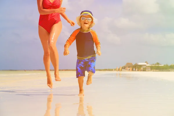 Äiti ja poika juoksevat vedessä rannalla — kuvapankkivalokuva